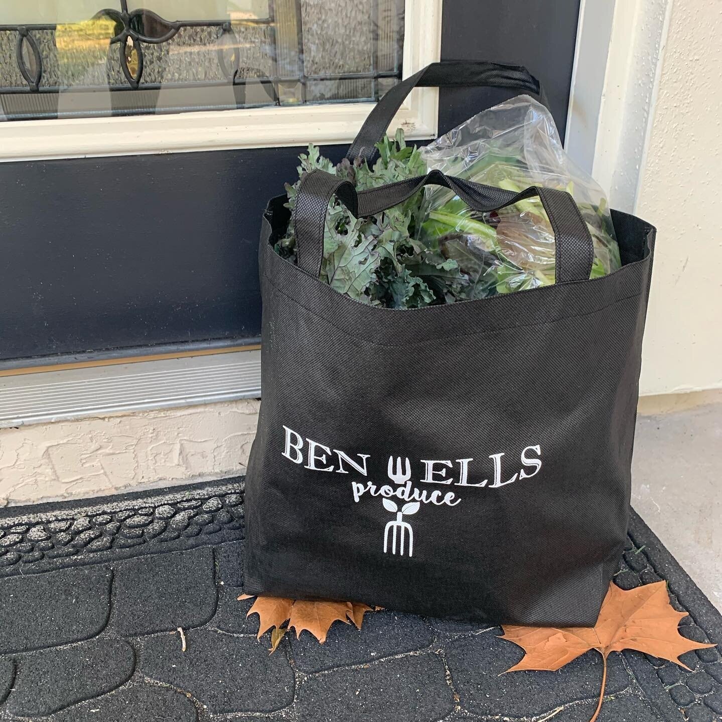 89750913_869599840153645_2098543603763642368_n Black reusable grocery bag with "BEN WELLS produce" logo, filled with fresh greens, placed on a doorstep with autumn leaves nearby.